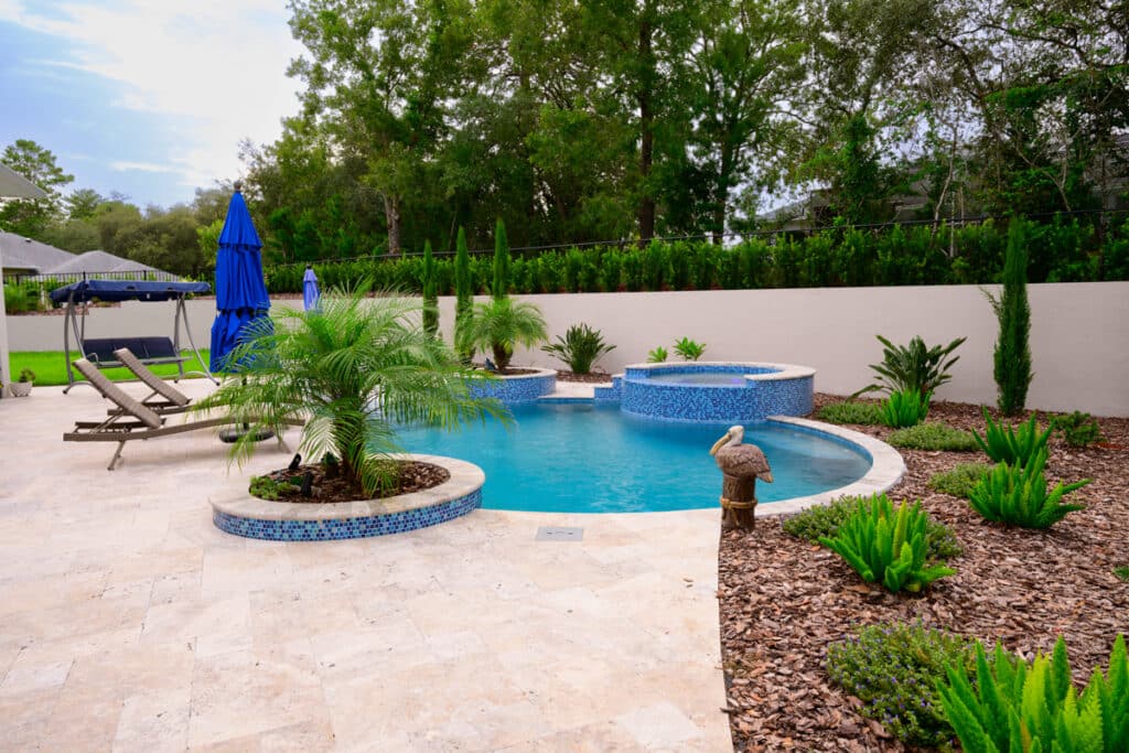 Beautiful backyard pool with a curved design, blue umbrellas, and lush landscaping