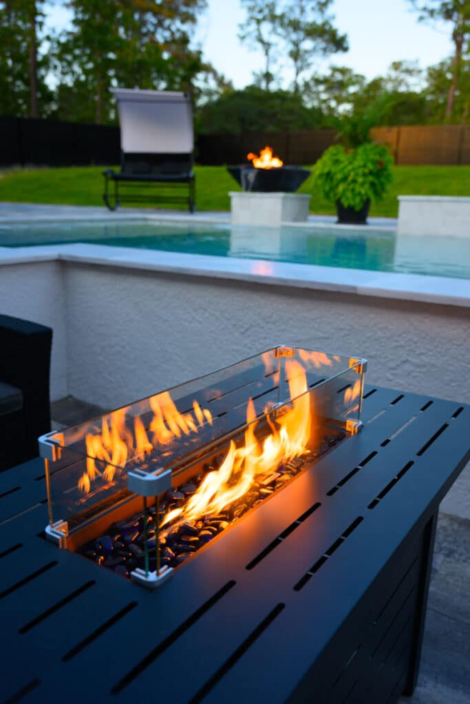 Black firepit with flames, situated near the pool with a relaxing seating area in Weeki Wachee, FL.