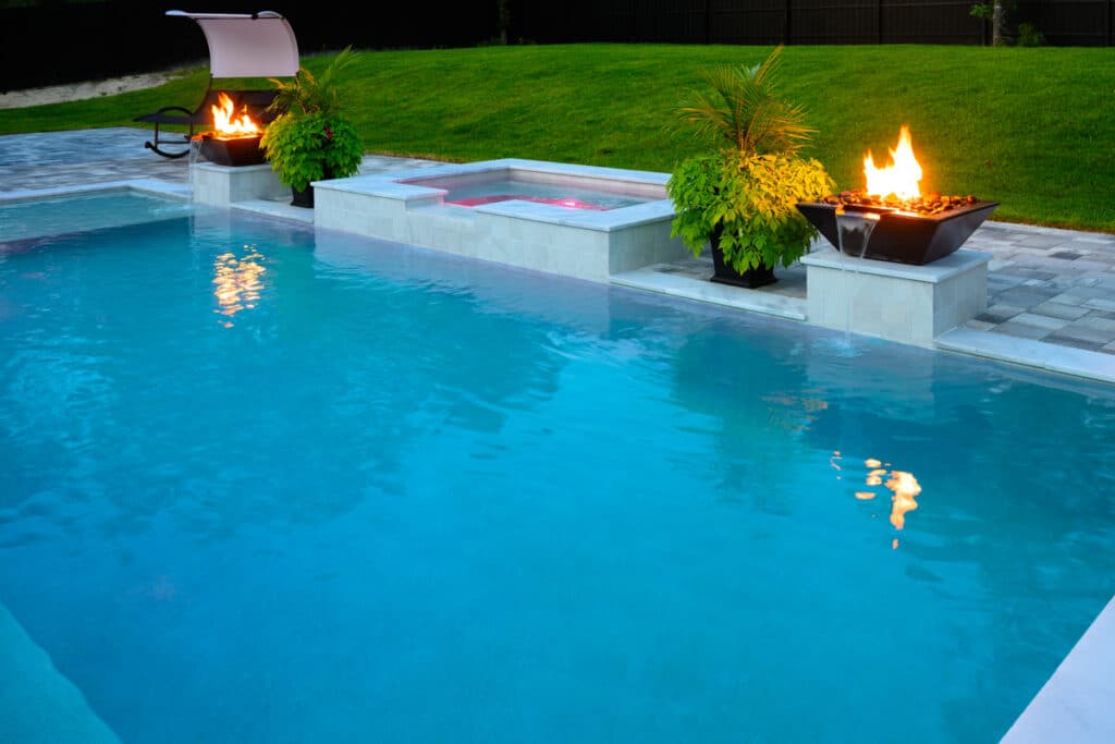 Clear blue pool with a fire water bowl, showcasing a luxurious backyard setting