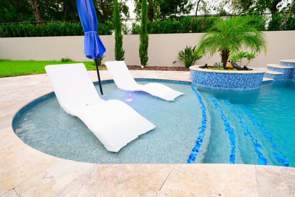 Close-up of lounge chairs in a shallow section of a backyard pool