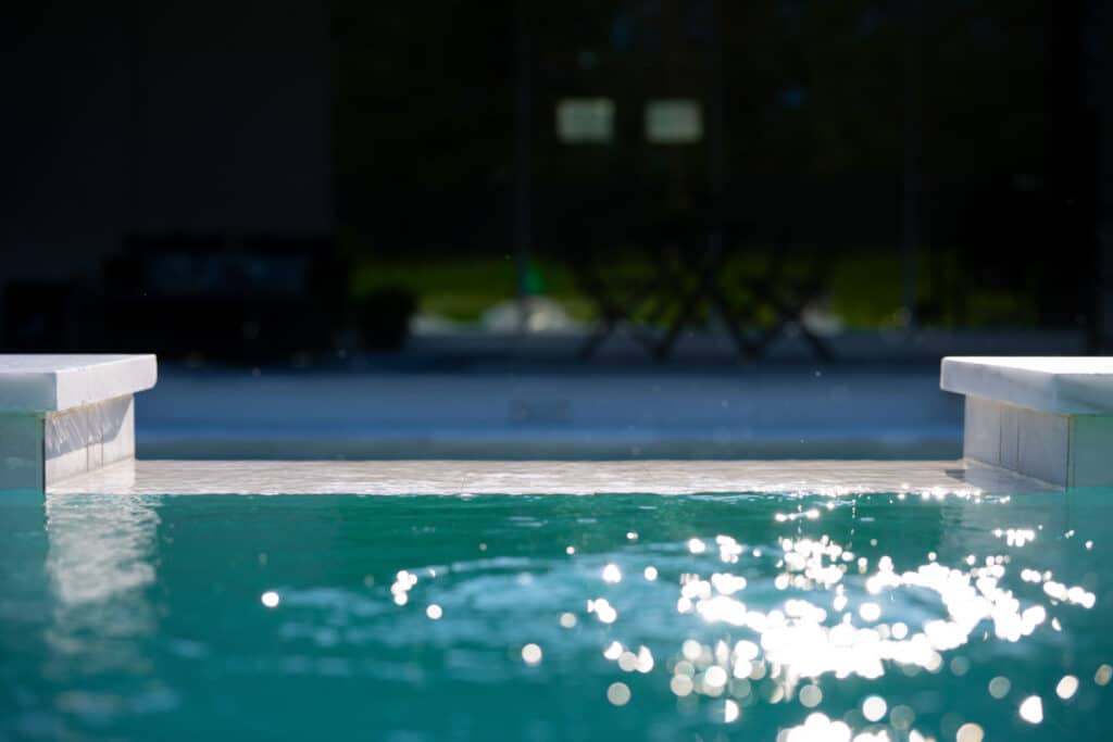 Close-up of the pool's edge with clear water, reflecting the surrounding lights