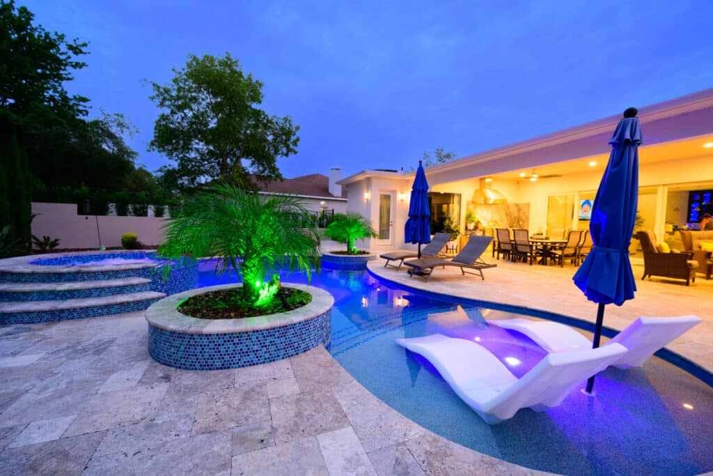 Modern backyard pool in Weeki Wachee with integrated steps, blue mosaic tiles, and a cozy seating area.