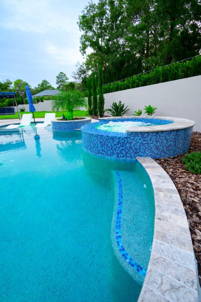 Modern backyard pool with integrated steps and blue mosaic tiles in a Weeki Wachee home