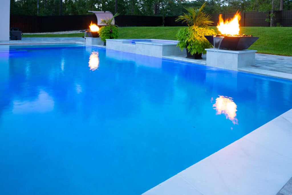 Night view of a pool with a black fire water bowl