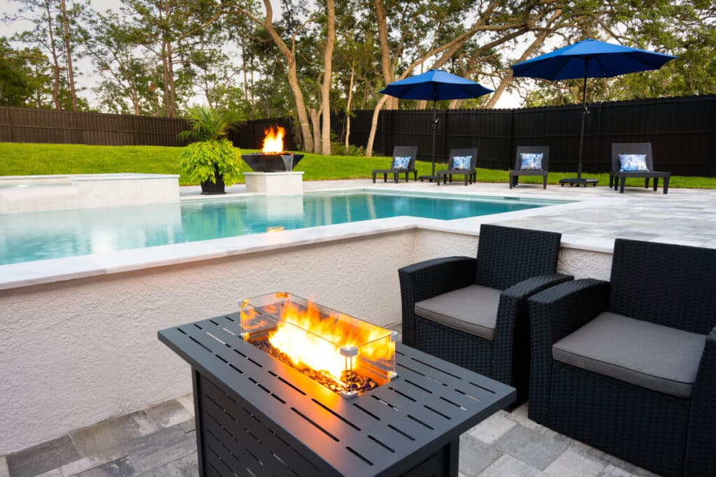 Poolside seating area with a fire pit, providing a cozy ambiance for evening gatherings.