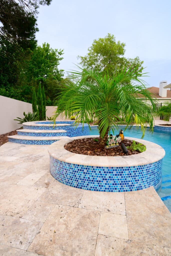 View of a backyard pool with integrated planters, vibrant greenery, and blue mosaic tiles