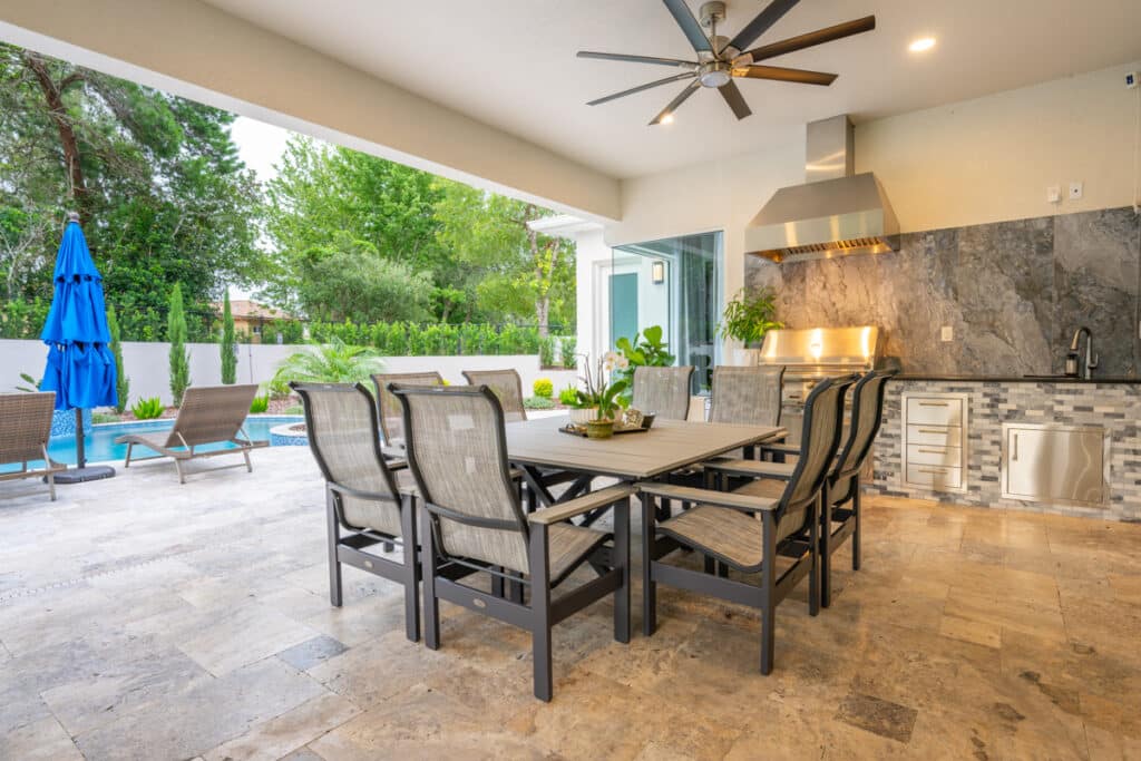 View of an outdoor living space with a dining table, lounge chairs, and a pool in the background