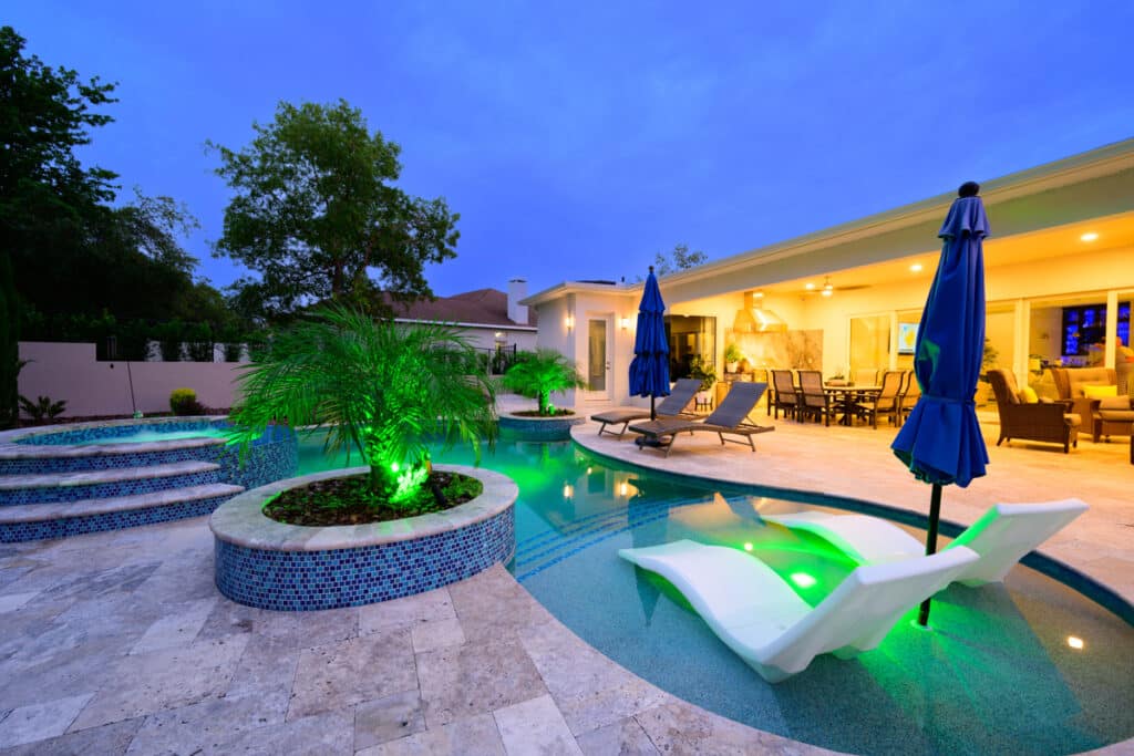 backyard featuring a pool with a hot tub, blue mosaic tiles, and vibrant LED lights