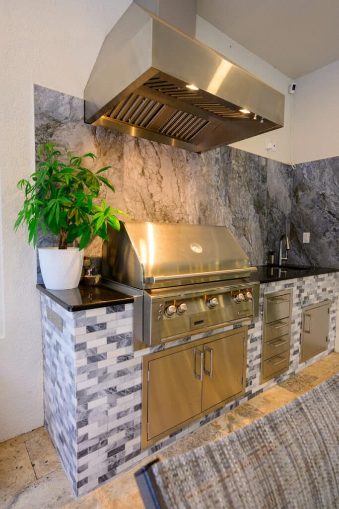 stylish outdoor kitchen area with stone accents and stainless steel appliances