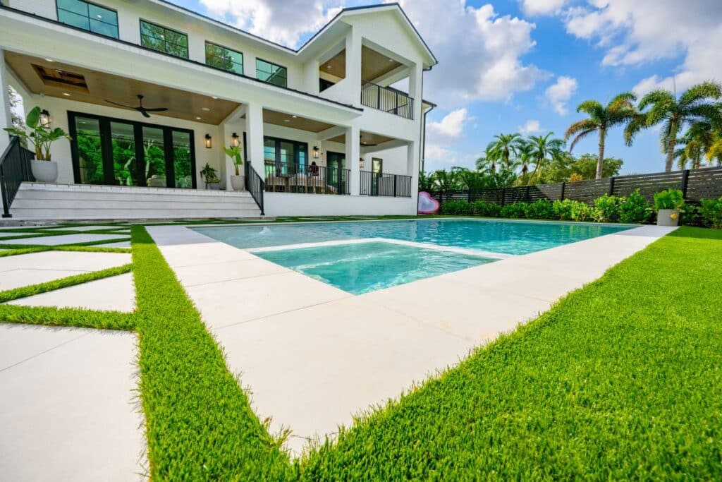 Balcony view of the backyard, showcasing lush greenery and pool area.