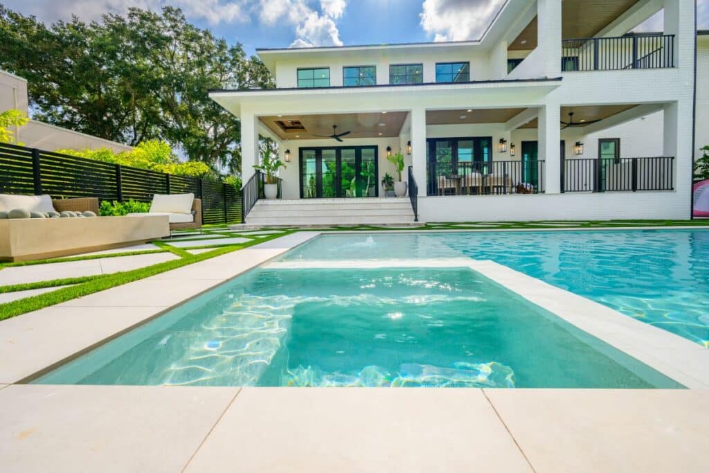 Contemporary backyard pool with a connected hot tub and spacious deck area.