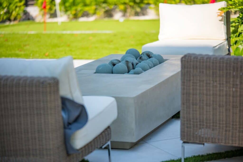 Cozy outdoor lounge area with wicker furniture and a green lawn.