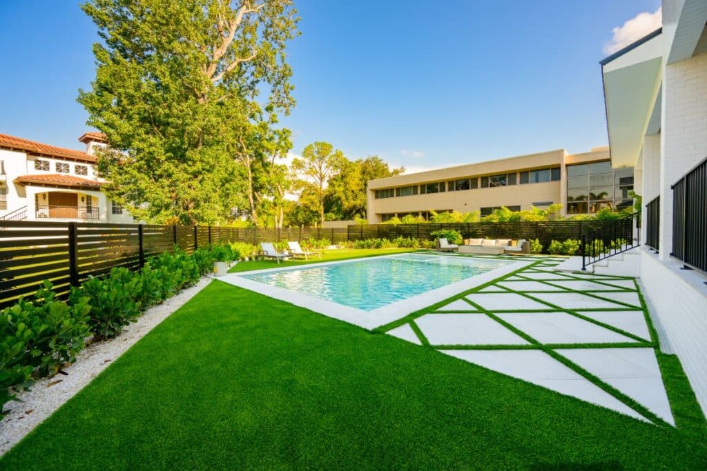 Garden pathway leading to a putting green, bordered by green shrubs.