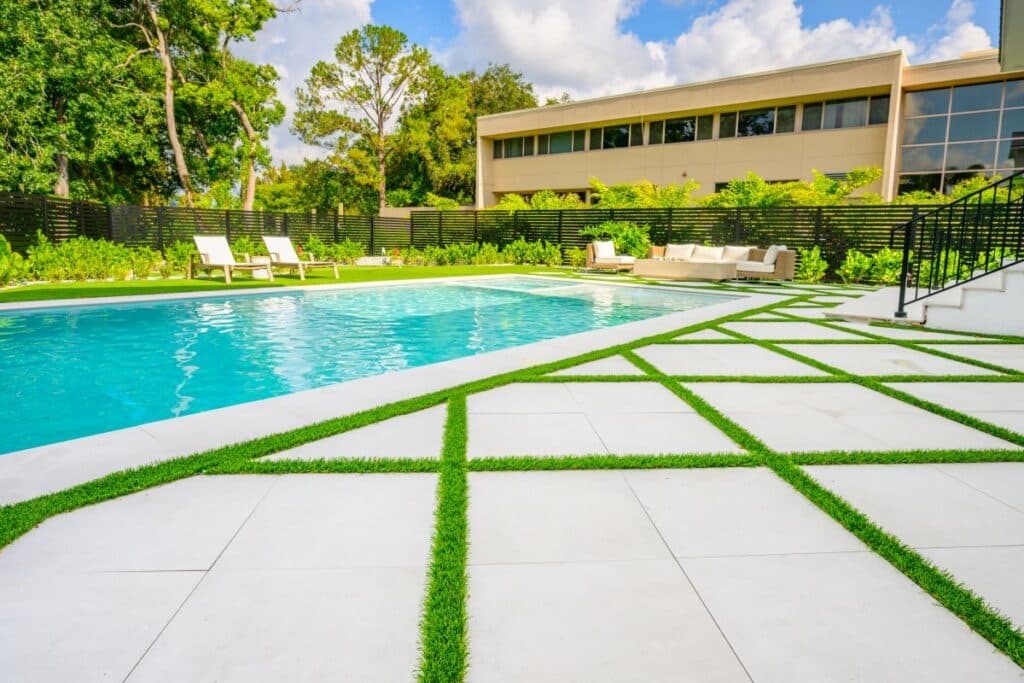 Green lawn area with sun loungers and stylish pavers leading to the pool.