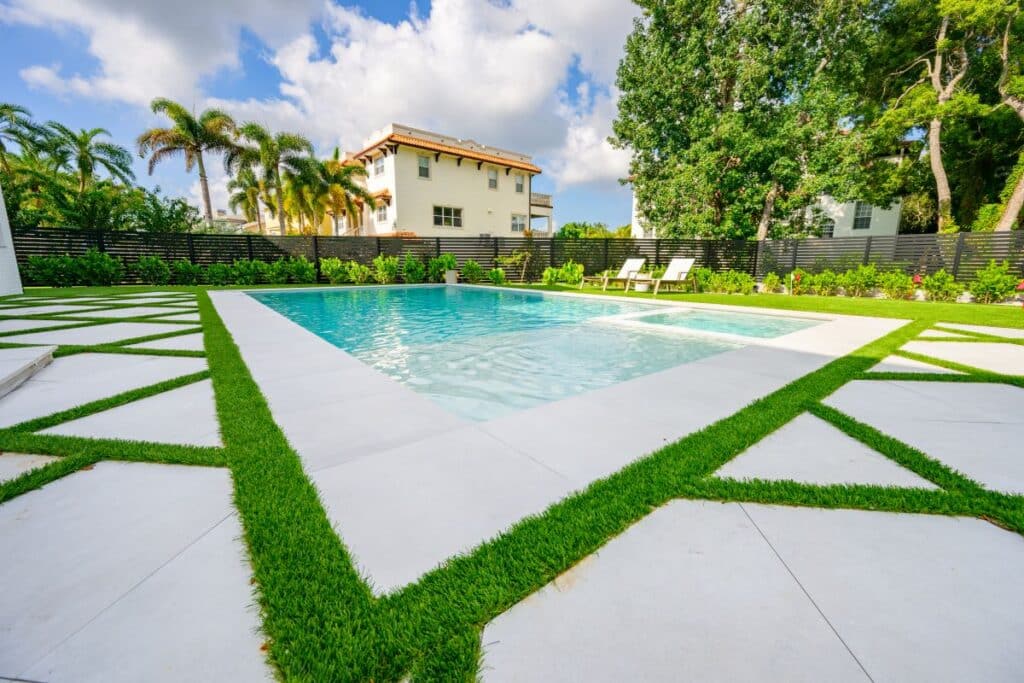 Modern backyard with geometric pavers and a lush green lawn.