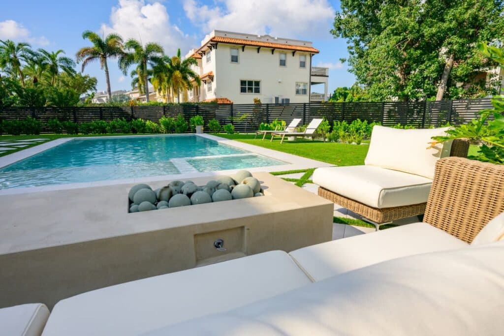 Outdoor seating area with a cozy cushioned setup, overlooking the pool and greenery.