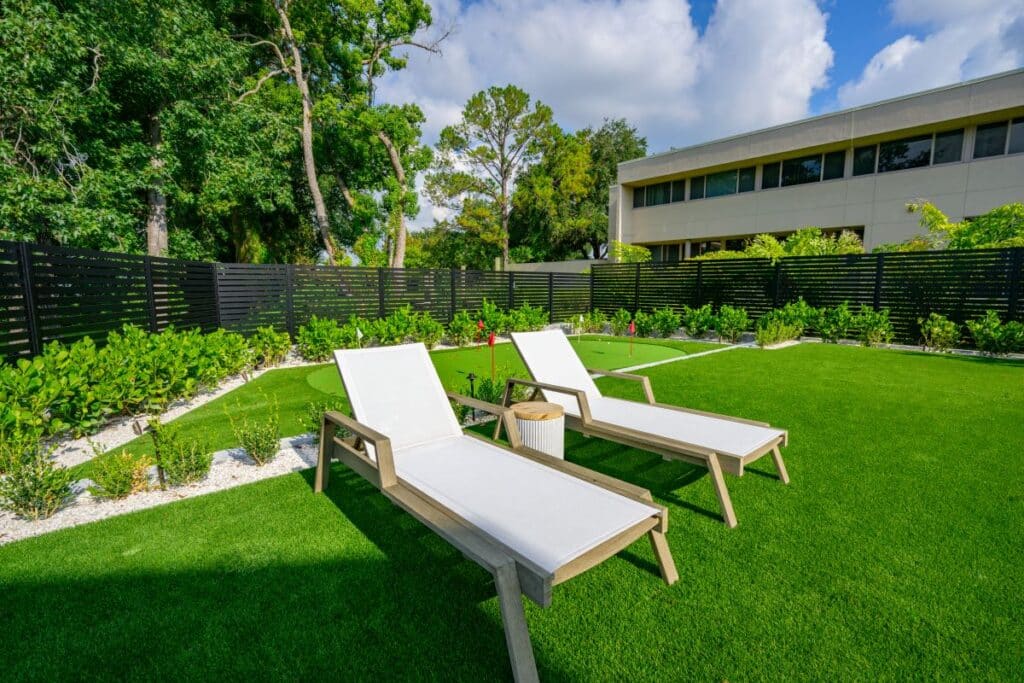 Outdoor sun loungers set on a green lawn with a view of the pool.