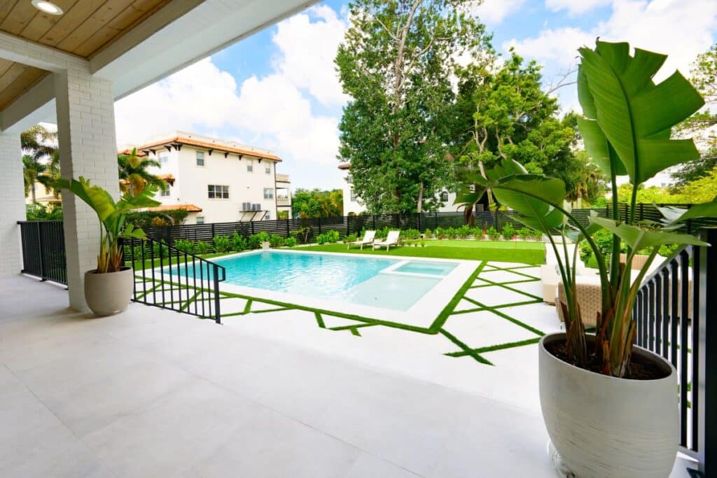 Shaded outdoor seating area with a comfortable sofa and scenic pool view.