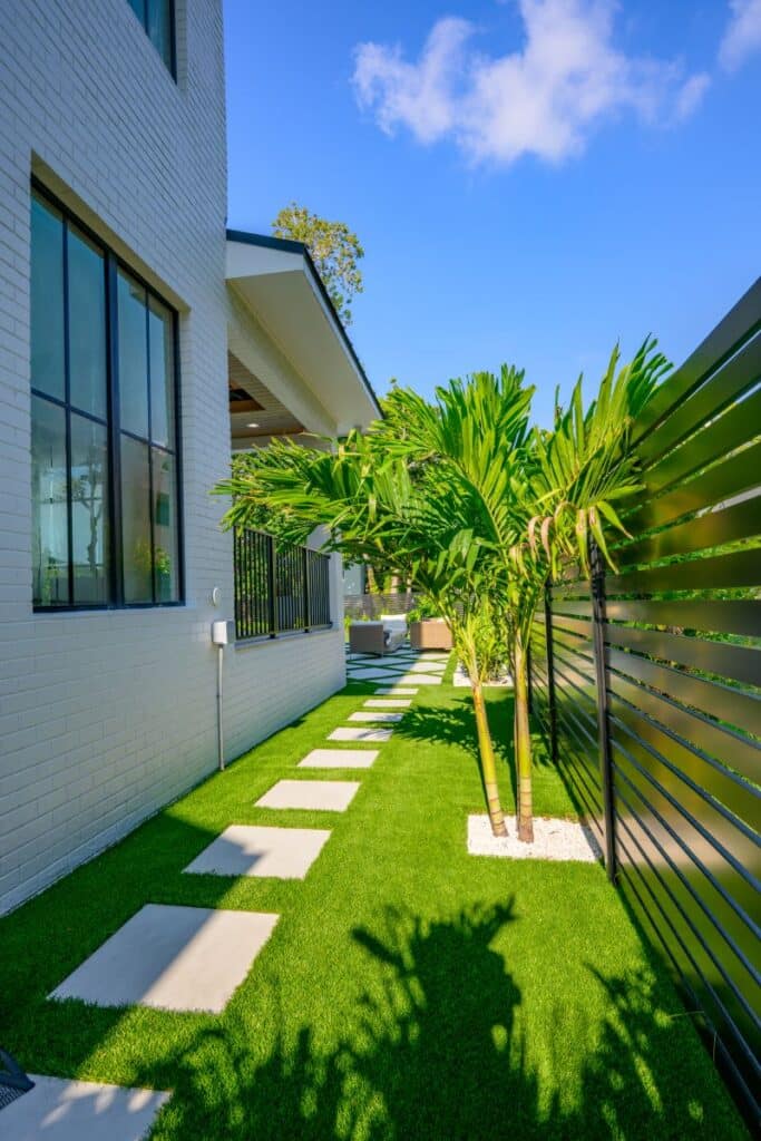 Side view of the house showing green landscaping and palm trees.