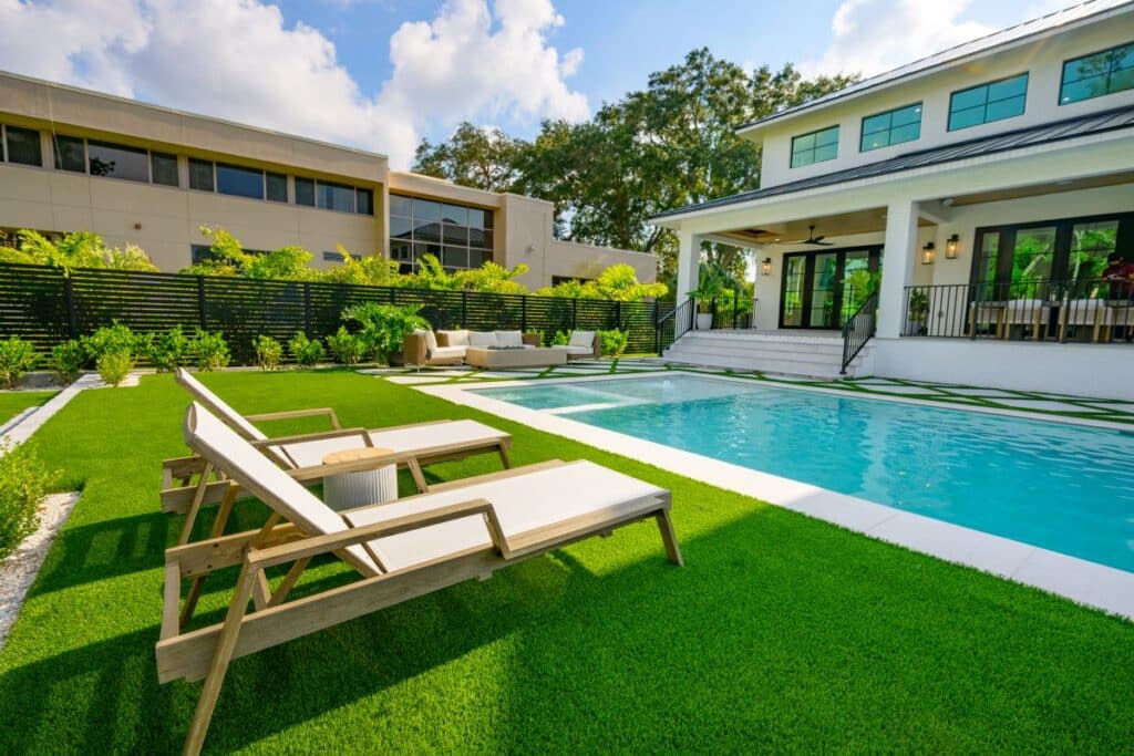 Sun loungers placed near a modern backyard pool.