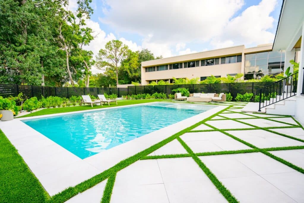 Wide shot of a contemporary pool framed by lush green landscaping.