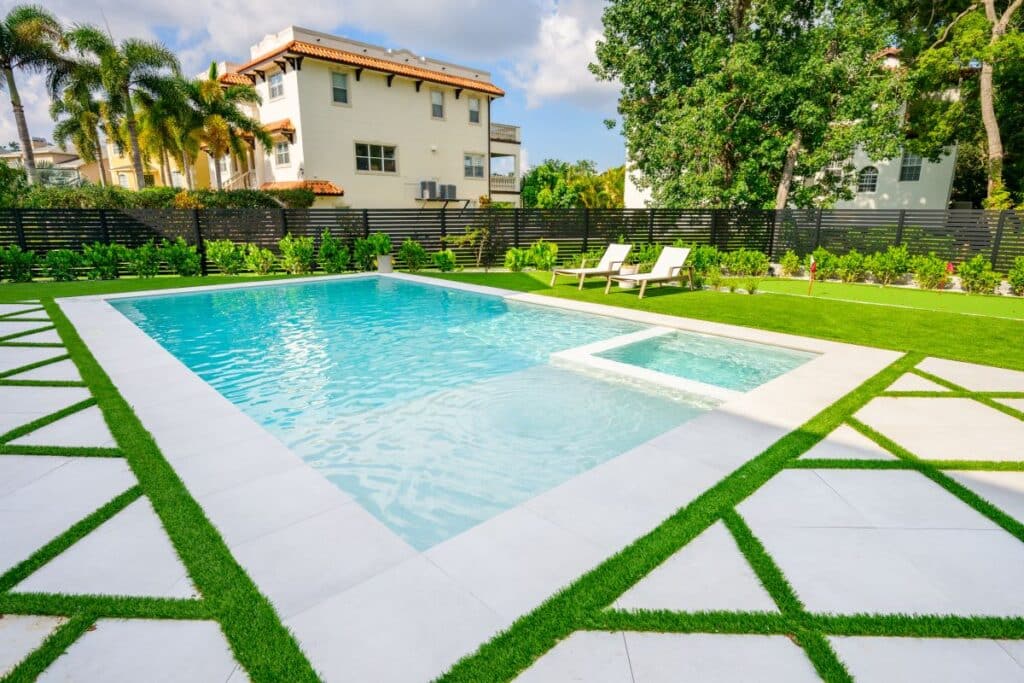 Wide view of a contemporary backyard pool with geometric paver design.