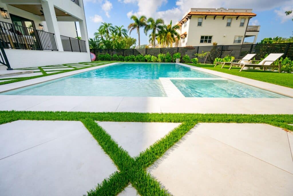 Wide view of the pool with green lawn and lush landscaping.