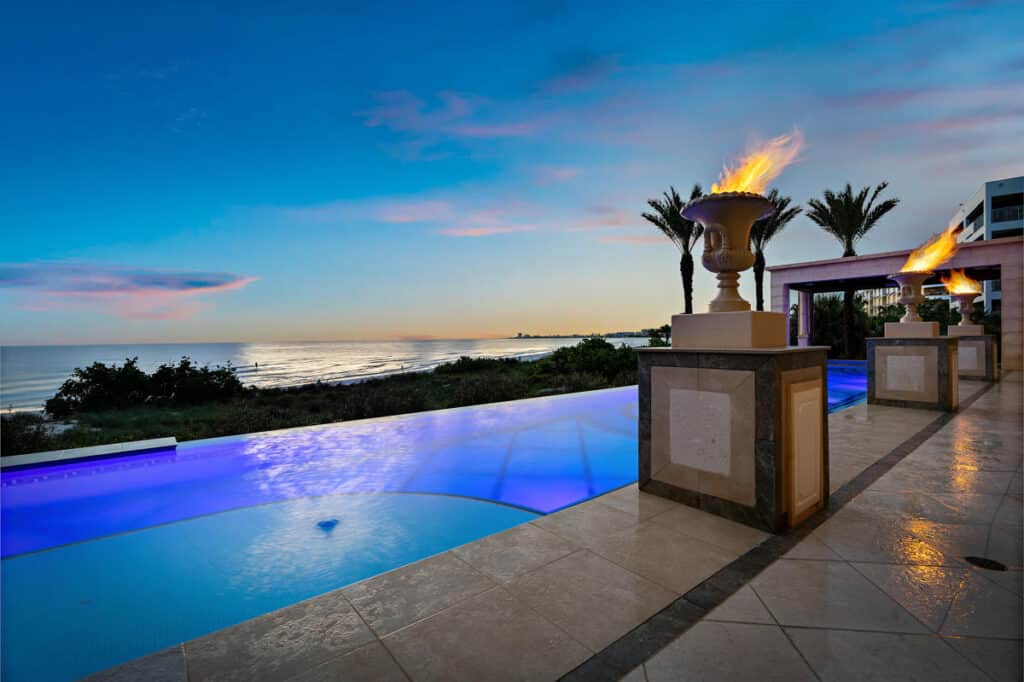 Custom Tampa pool featuring fire bowls and ambient lighting, designed for a dramatic and cozy nighttime experience