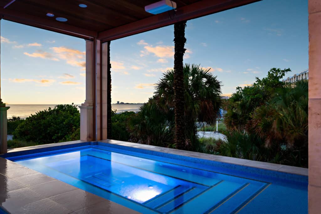 Modern pool in Tampa with sheltered seating and lush greenery, offering a private and relaxing outdoor escape.