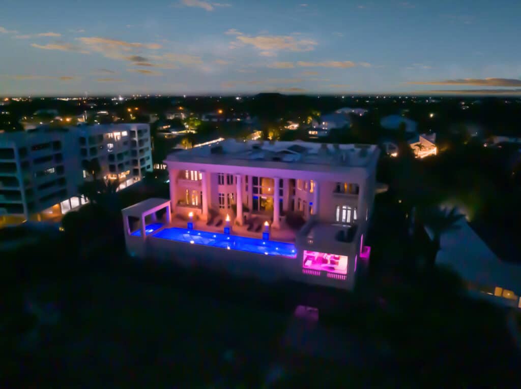 Night aerial view of a luxury Tampa pool with vibrant lighting showcasing modern pool design and landscape features