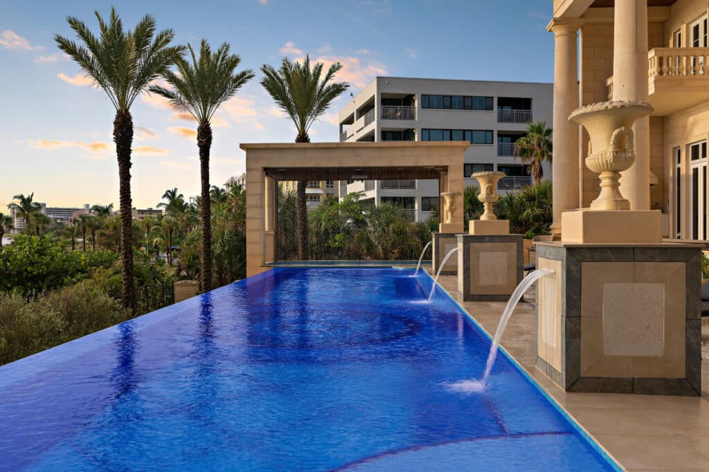 night view of a luxury pool in Tampa with vibrant lighting, showcasing modern pool design and landscaping