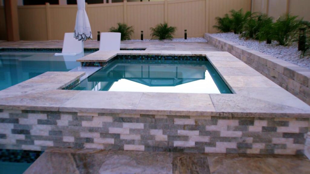 A close-up of a jacuzzi integrated with a modern pool, bordered by natural stone tiles.