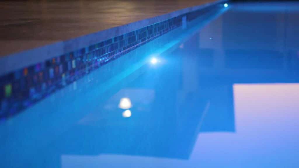 A close-up of decorative tile details along the pool’s edge, illuminated by pool lights.