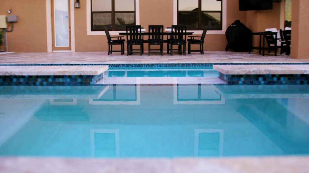 A contemporary pool with a unique spillover spa feature and surrounding LED lights.